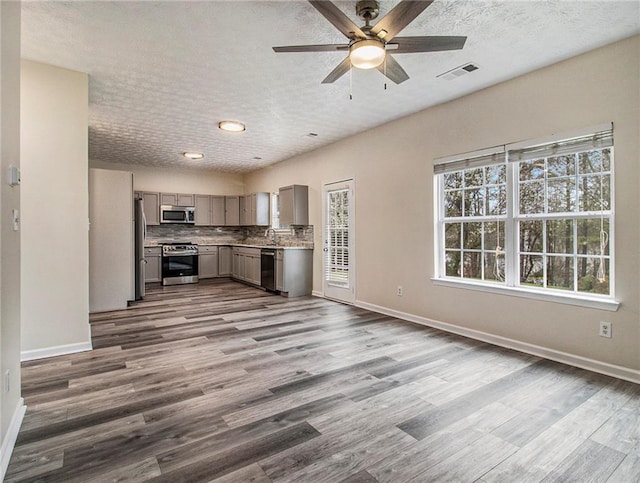 unfurnished living room with a textured ceiling, ceiling fan, and dark wood-type flooring