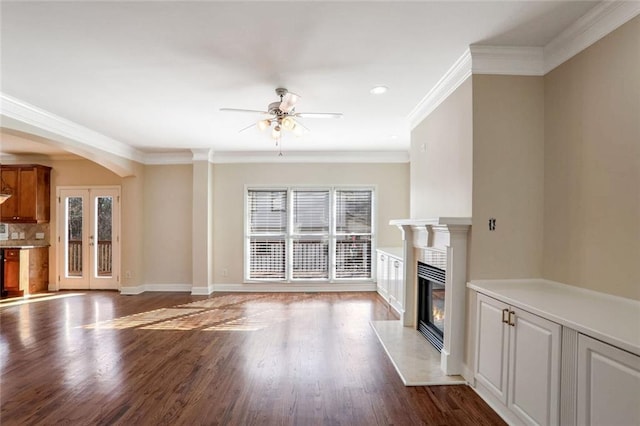 unfurnished living room featuring crown molding, baseboards, a high end fireplace, a ceiling fan, and wood finished floors