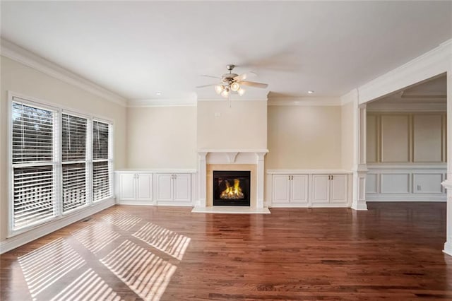 unfurnished living room featuring a fireplace, a decorative wall, a ceiling fan, and ornamental molding