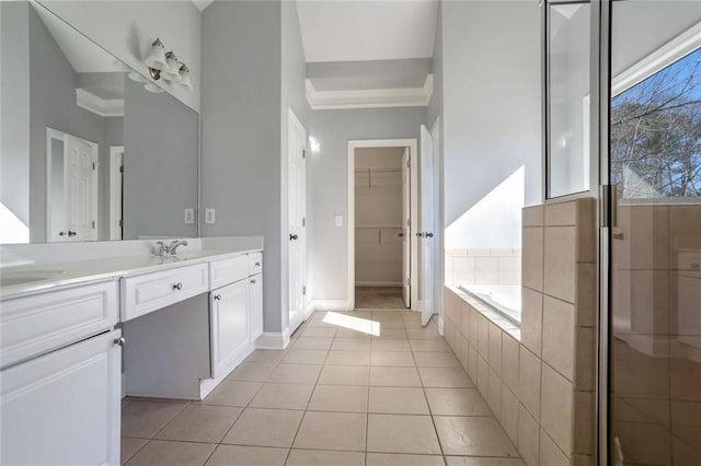 bathroom with vanity, a spacious closet, ornamental molding, tile patterned floors, and a garden tub