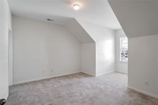 additional living space featuring baseboards, carpet, lofted ceiling, and visible vents