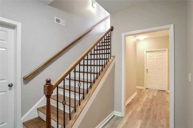 stairs with baseboards, visible vents, and wood finished floors
