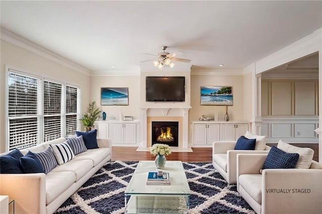living room with wood finished floors, ornamental molding, and ceiling fan