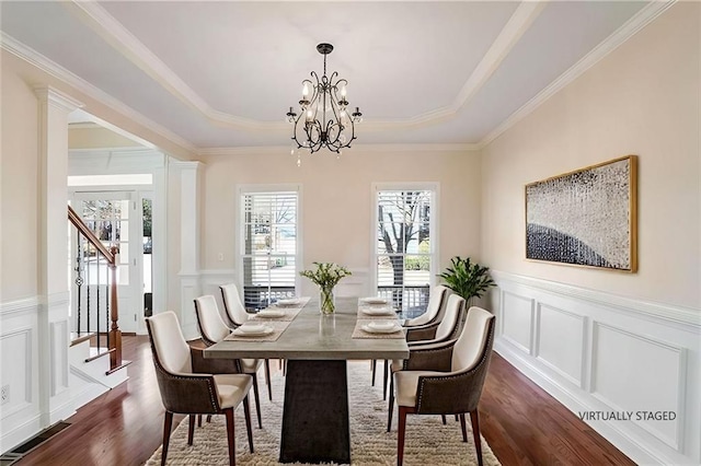 dining room with a decorative wall, stairs, a raised ceiling, dark wood-style floors, and a notable chandelier