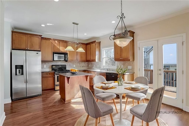 kitchen with a kitchen island, ornamental molding, appliances with stainless steel finishes, and decorative backsplash