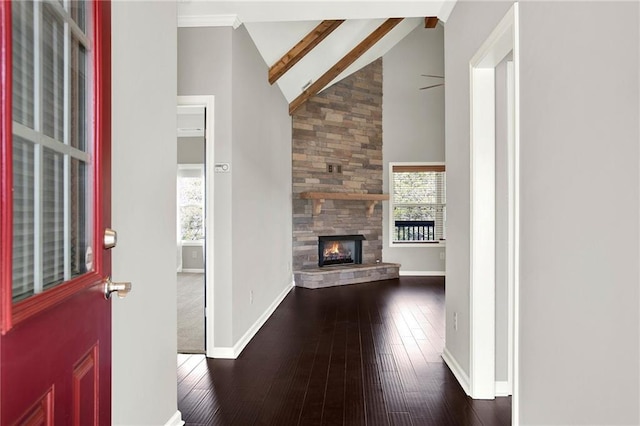 entryway with beamed ceiling, high vaulted ceiling, a stone fireplace, and dark wood-type flooring