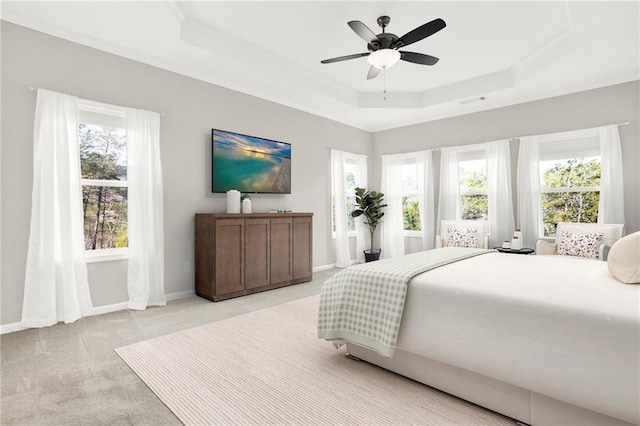 bedroom with a raised ceiling, light carpet, and multiple windows