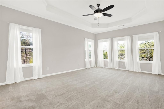 carpeted spare room featuring ornamental molding, a healthy amount of sunlight, ceiling fan, and a tray ceiling