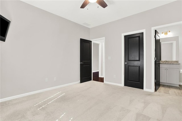 unfurnished bedroom with sink, ensuite bath, light colored carpet, and ceiling fan