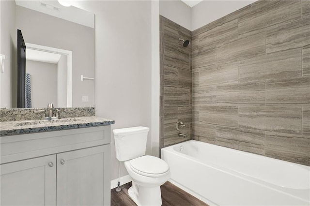 full bathroom featuring wood-type flooring, toilet, tiled shower / bath combo, and vanity