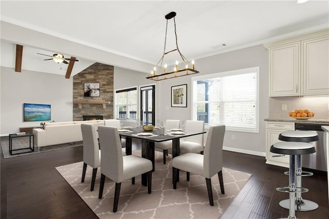 dining area featuring dark hardwood / wood-style floors, a fireplace, lofted ceiling with beams, ornamental molding, and ceiling fan