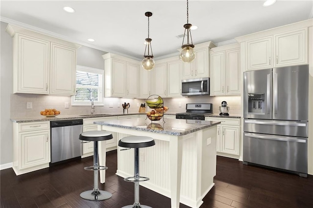 kitchen with a kitchen island, sink, hanging light fixtures, stainless steel appliances, and light stone countertops