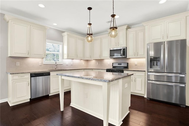 kitchen featuring sink, appliances with stainless steel finishes, a kitchen island, pendant lighting, and light stone countertops