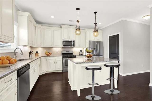 kitchen featuring a kitchen island, pendant lighting, sink, light stone counters, and stainless steel appliances