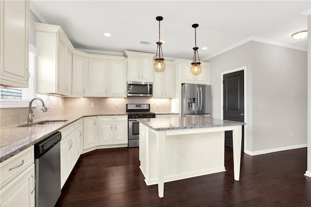 kitchen featuring pendant lighting, sink, stainless steel appliances, a center island, and light stone countertops