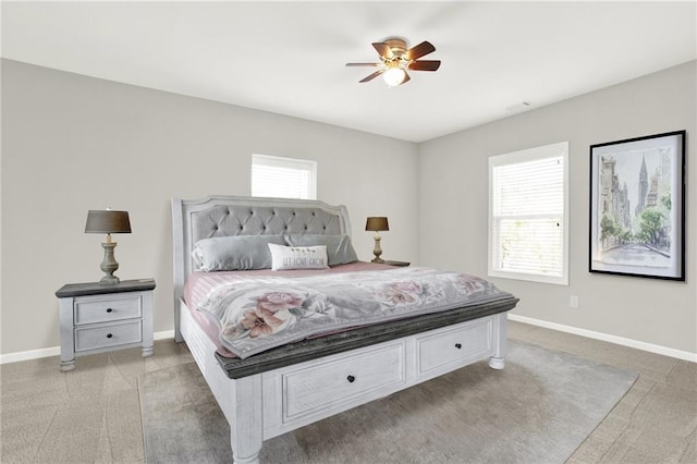 bedroom with ceiling fan, light colored carpet, and multiple windows