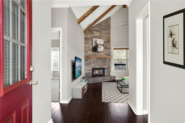 foyer entrance featuring beam ceiling, high vaulted ceiling, dark hardwood / wood-style flooring, ceiling fan, and a fireplace