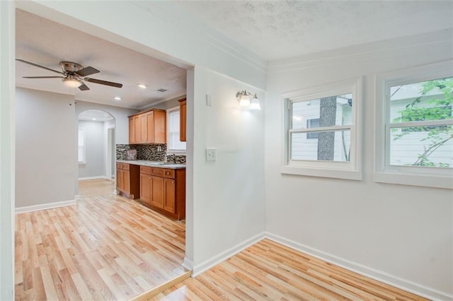 kitchen with tasteful backsplash, ceiling fan, sink, and light hardwood / wood-style floors