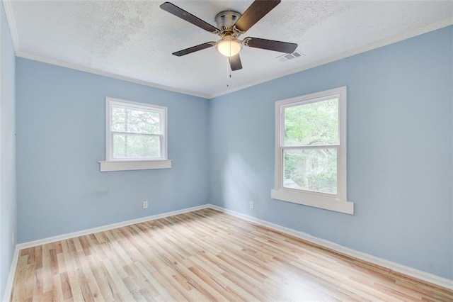 empty room with ceiling fan, a wealth of natural light, a textured ceiling, and light hardwood / wood-style floors