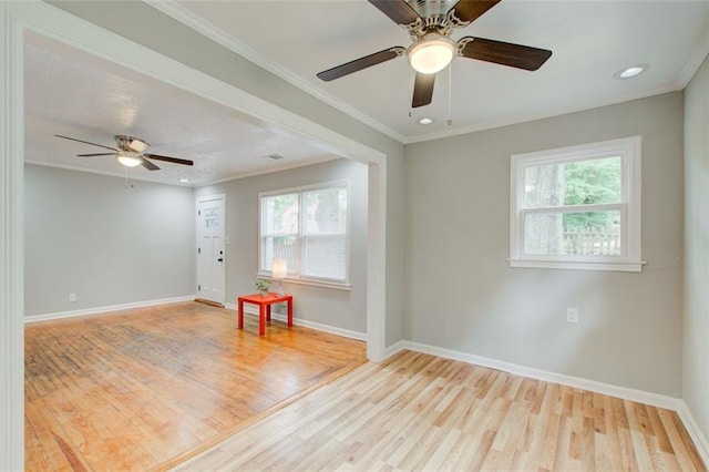 empty room with ornamental molding, a wealth of natural light, and light hardwood / wood-style floors