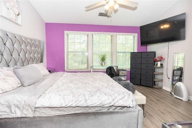 bedroom with wood finished floors, baseboards, a ceiling fan, and lofted ceiling