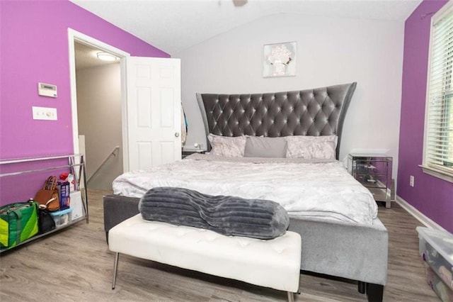 bedroom featuring wood finished floors, lofted ceiling, and baseboards