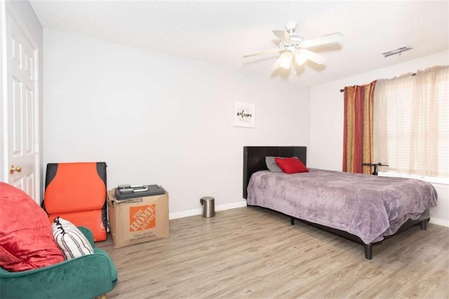 bedroom featuring wood finished floors, baseboards, and a ceiling fan