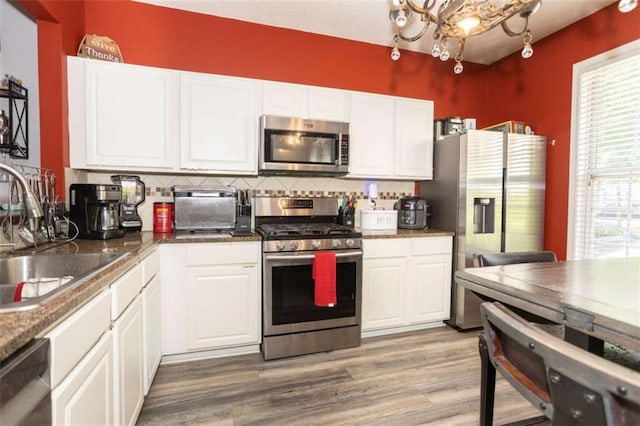 kitchen with appliances with stainless steel finishes, a sink, white cabinets, and decorative backsplash