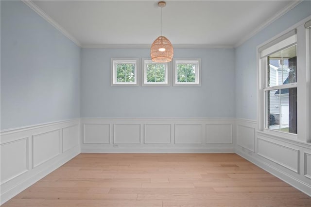 spare room featuring a wainscoted wall, light wood-style flooring, and ornamental molding