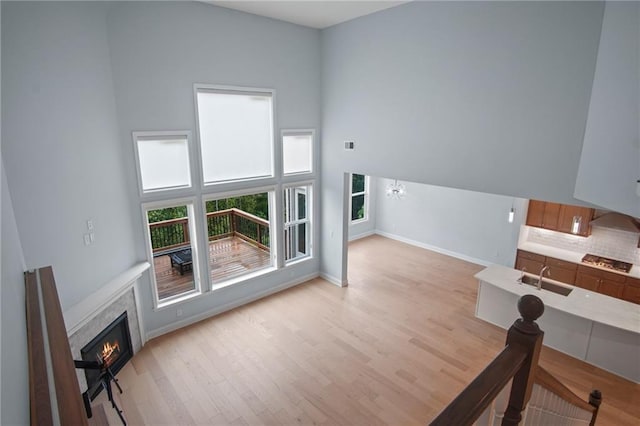 living area with light wood finished floors, visible vents, baseboards, a tiled fireplace, and a high ceiling