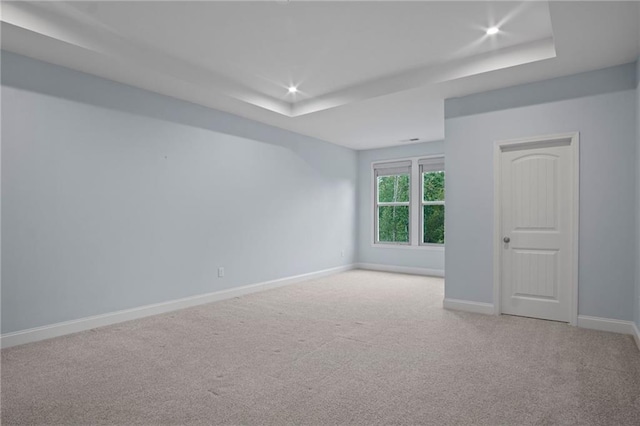 carpeted spare room featuring a raised ceiling, recessed lighting, and baseboards