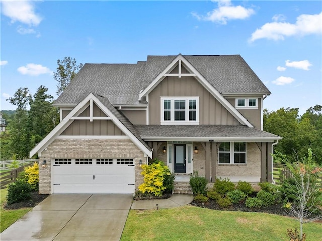 craftsman-style home with a front yard, driveway, a shingled roof, board and batten siding, and brick siding