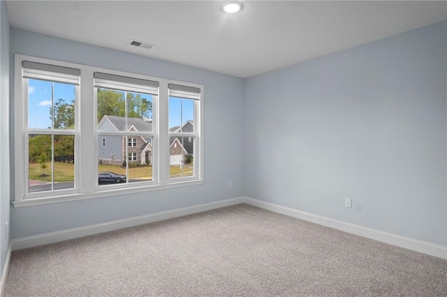 carpeted spare room with visible vents and baseboards