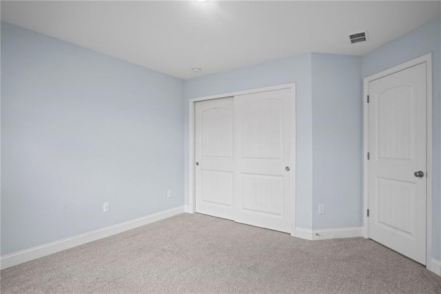 unfurnished bedroom featuring carpet, visible vents, a closet, and baseboards