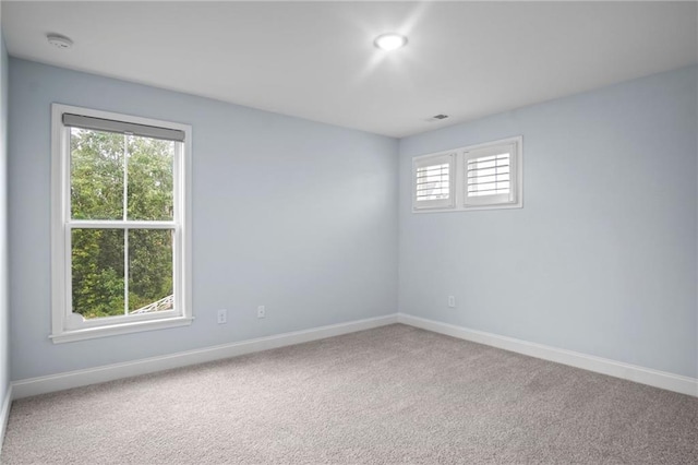 unfurnished room featuring carpet flooring, visible vents, and baseboards