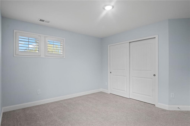 unfurnished bedroom with visible vents, carpet floors, baseboards, and a closet