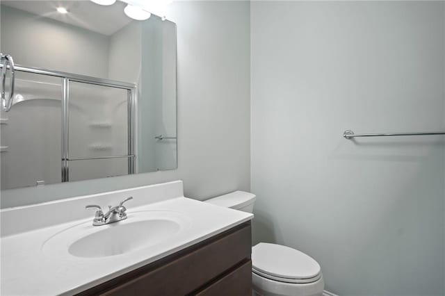 bathroom with a shower stall, toilet, and vanity