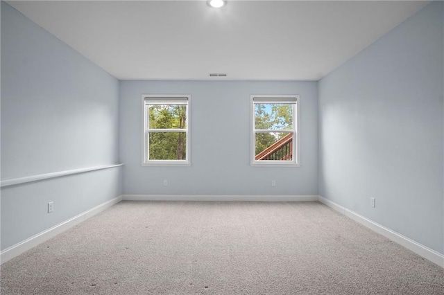 spare room with a wealth of natural light, baseboards, visible vents, and carpet floors