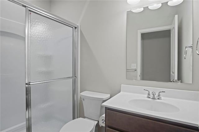 bathroom with vanity, a shower stall, and toilet