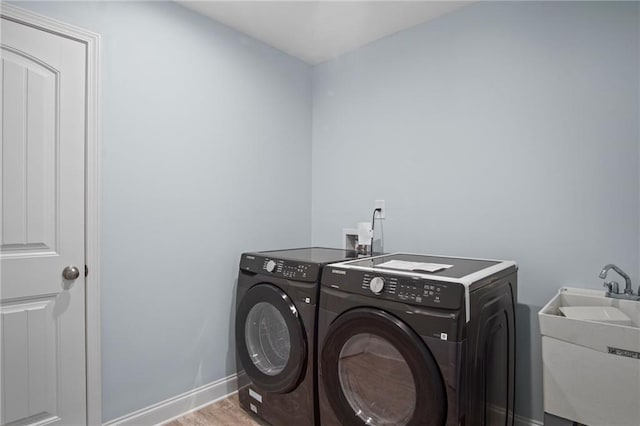 washroom with light wood finished floors, baseboards, laundry area, independent washer and dryer, and a sink
