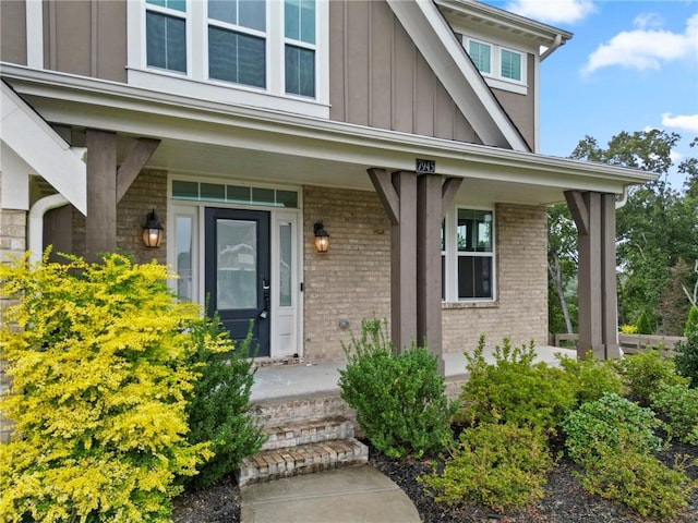 property entrance with brick siding, board and batten siding, and covered porch