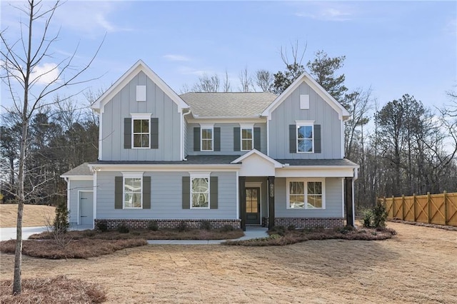 view of front facade featuring board and batten siding, fence, a porch, and brick siding