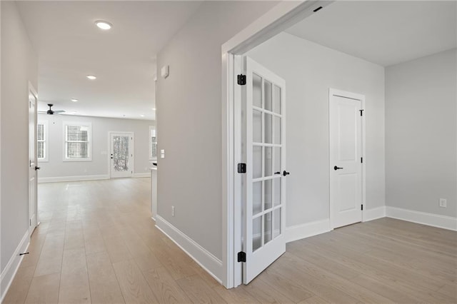 hallway featuring light wood-style flooring, recessed lighting, and baseboards