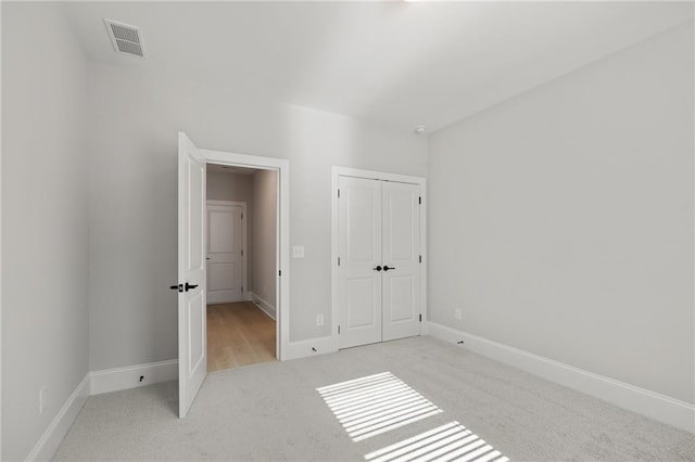 unfurnished bedroom featuring light carpet, baseboards, and a closet