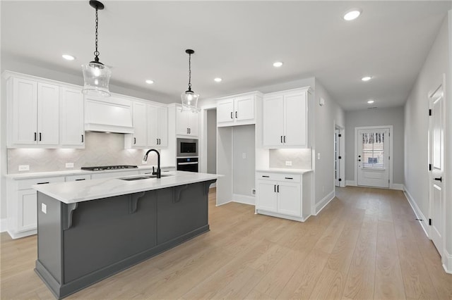 kitchen with a sink, custom range hood, stainless steel appliances, white cabinetry, and recessed lighting