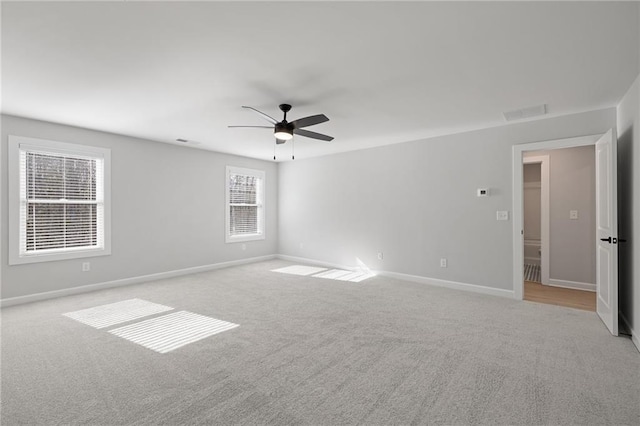 empty room with light colored carpet, ceiling fan, and baseboards