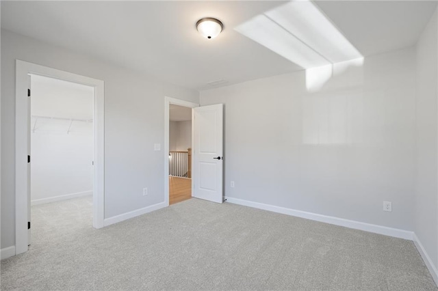 unfurnished bedroom featuring carpet floors, a spacious closet, baseboards, and a closet