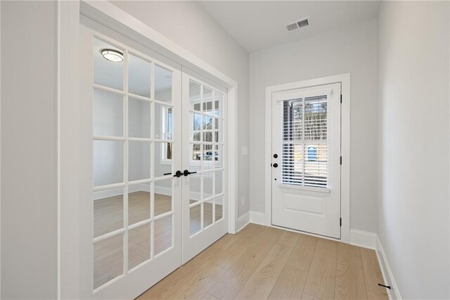 entryway featuring french doors, light wood finished floors, and baseboards