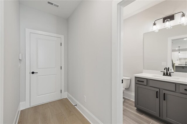 bathroom featuring wood finished floors, toilet, vanity, and baseboards