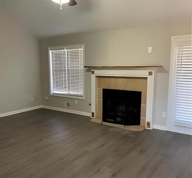 unfurnished living room featuring ceiling fan, dark hardwood / wood-style flooring, and a tiled fireplace